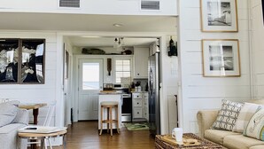 A spacious living area with a high ceiling, a wooden staircase, a kitchen, and a dining area. - Beautiful Beach House with Gulf views, 2 min walk to Beach!!  (Galveston)