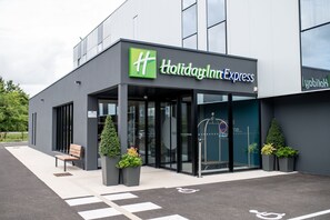 Welcome to Holiday Inn Express, featuring a modern exterior with a flat facade and large glass windows.