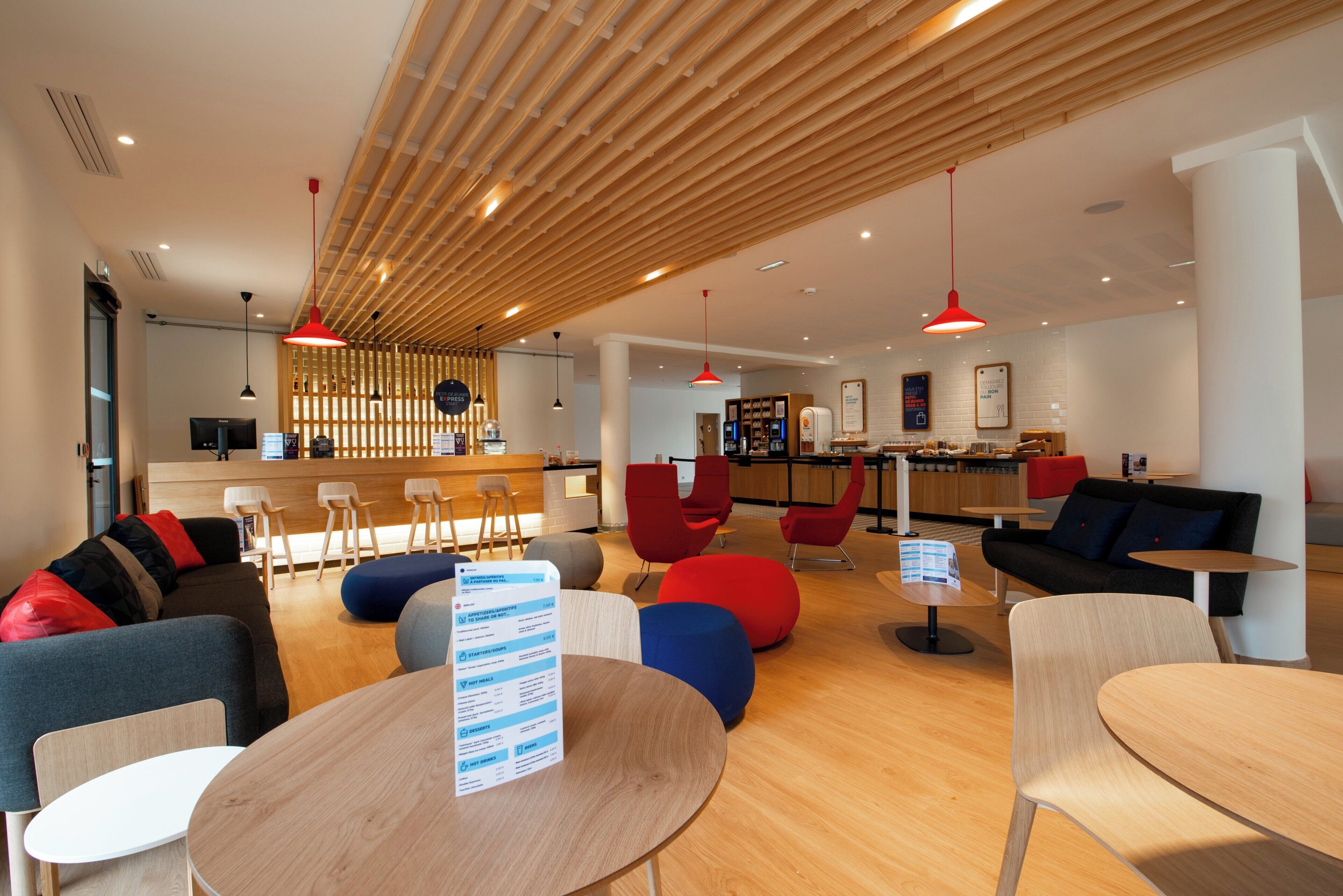 Un área de lounge moderna con asientos, mesas y un panel de menú.