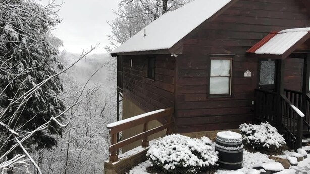 A wooden cabin with a balcony, surrounded by snow-covered trees. - A view for 2 & Cozy, Close to PF and Gatlinburg (Gatlinburg)