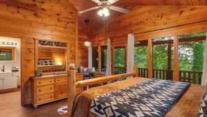 A wooden cabin interior with a bed, a desk, and a view of the outdoors. - A view for 2 & Cozy, Close to PF and Gatlinburg (Gatlinburg)