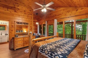 L’intérieur d’un chalet en bois, avec un lit, un bureau et une vue sur l’extérieur.