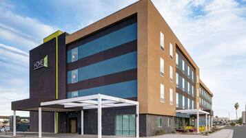 A modern hotel with a flat roof, large windows, and a covered entrance area.