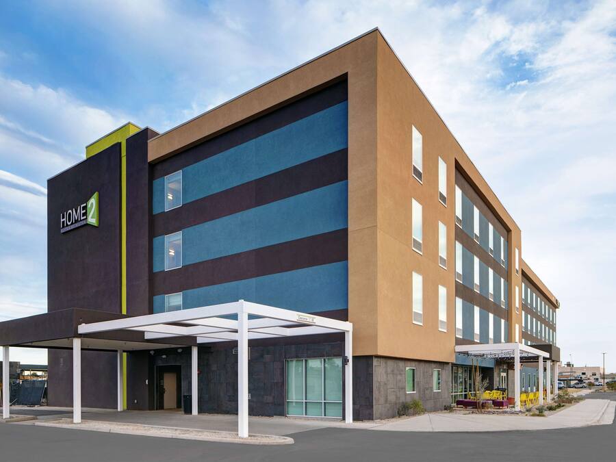 A modern hotel with a flat roof, large windows, and a covered entrance area.
