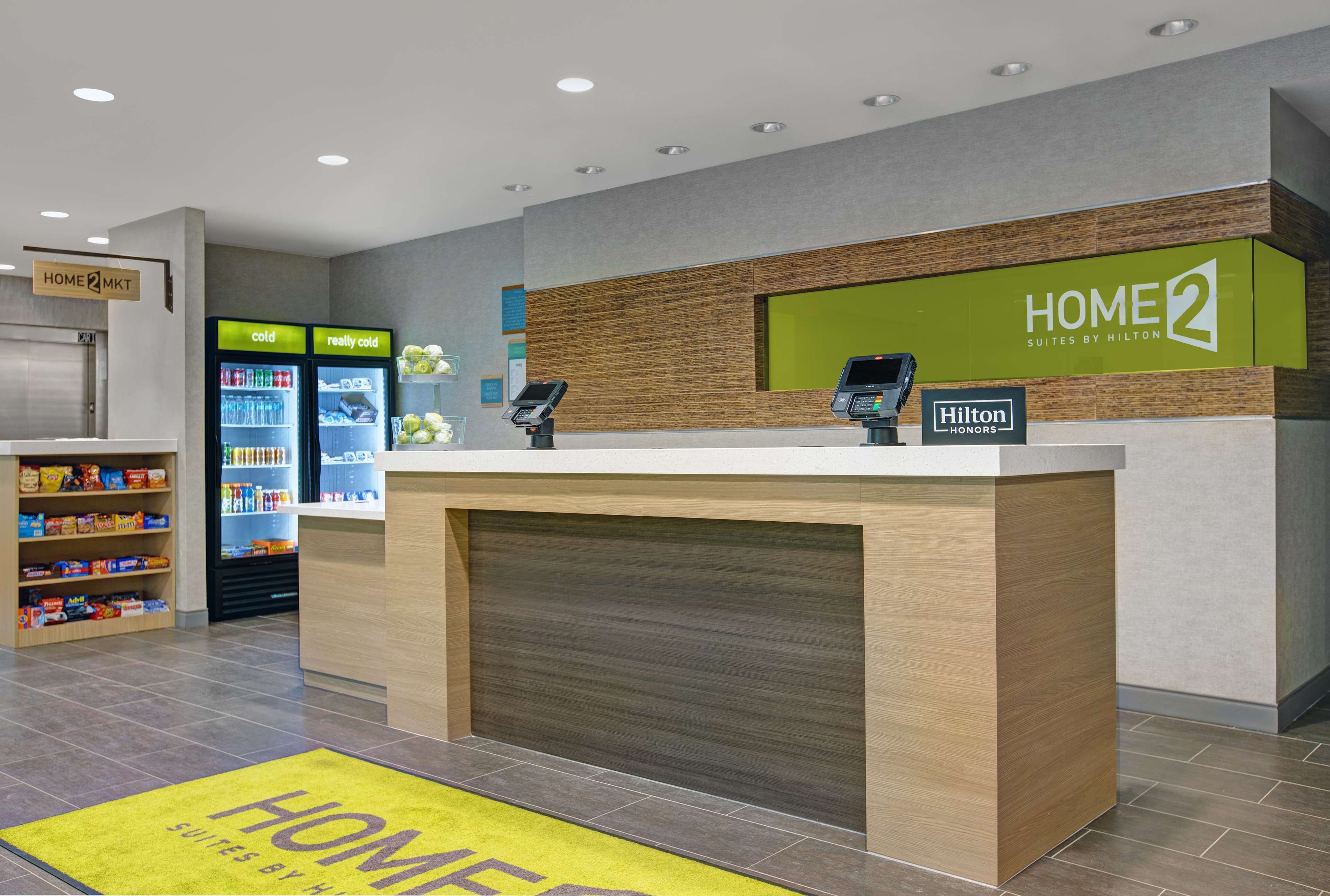 Zona de recepción de hotel con mostrador, minibar y estación de bebidas de autoservicio.