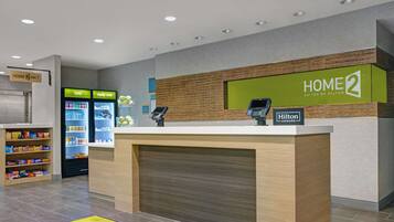 Zona de recepción de hotel con mostrador, minibar y estación de bebidas de autoservicio.