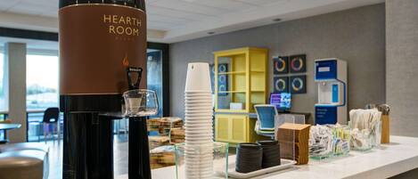 A coffee station with a branded coffee machine, disposable cups, and a stack of plates.