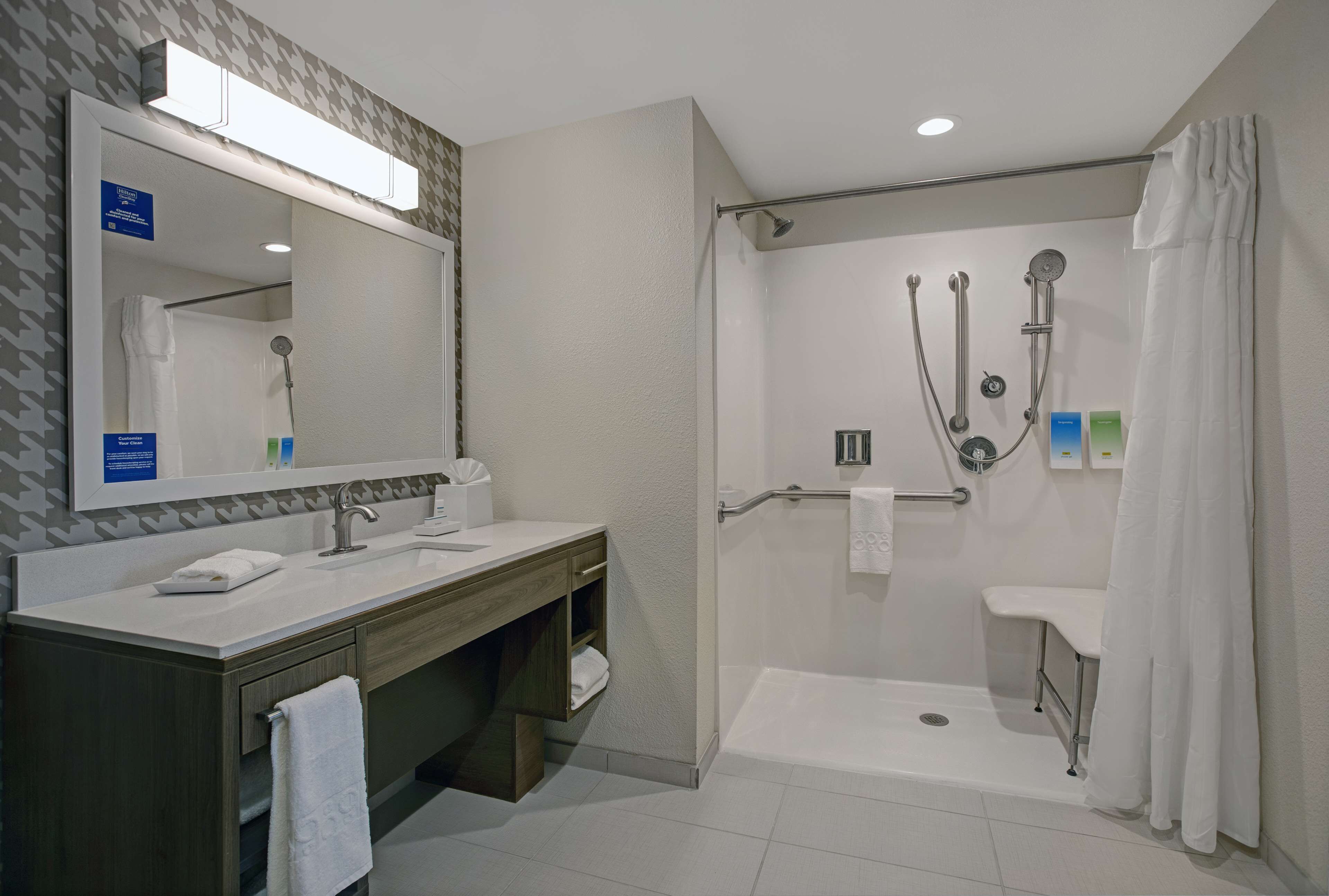 A modern bathroom with a shower, a vanity with a mirror, and a toilet.