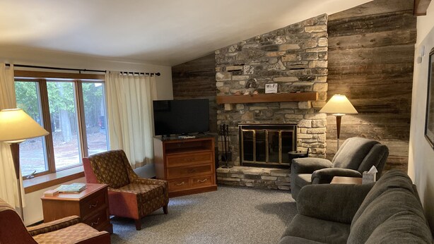Una sala de estar acogedora con chimenea de piedra, un televisor y dos sofás.