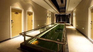 A hotel corridor with a long, narrow pool with a metal railing, doors on either side, and a staircase at the end. - Vinotel Cirebon (West Cirebon)
