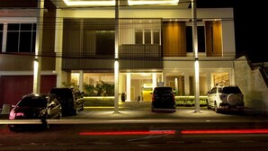 A modern hotel entrance with a covered driveway, multiple cars parked, and a well-lit facade. - Vinotel Cirebon (West Cirebon)