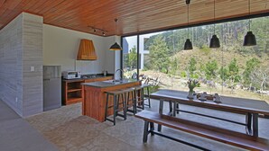 Una cocina moderna con una isla grande, taburetes de bar y una mesa de comedor con bancos.