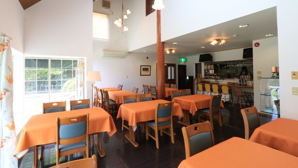 A restaurant with multiple tables and chairs, a bar area, and a view of the outdoors. - Pension Tinkuna (Minamiaso)