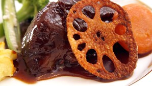 A plate with a glazed meat, a fried item with holes, and some vegetables. - Pension Tinkuna (Minamiaso)