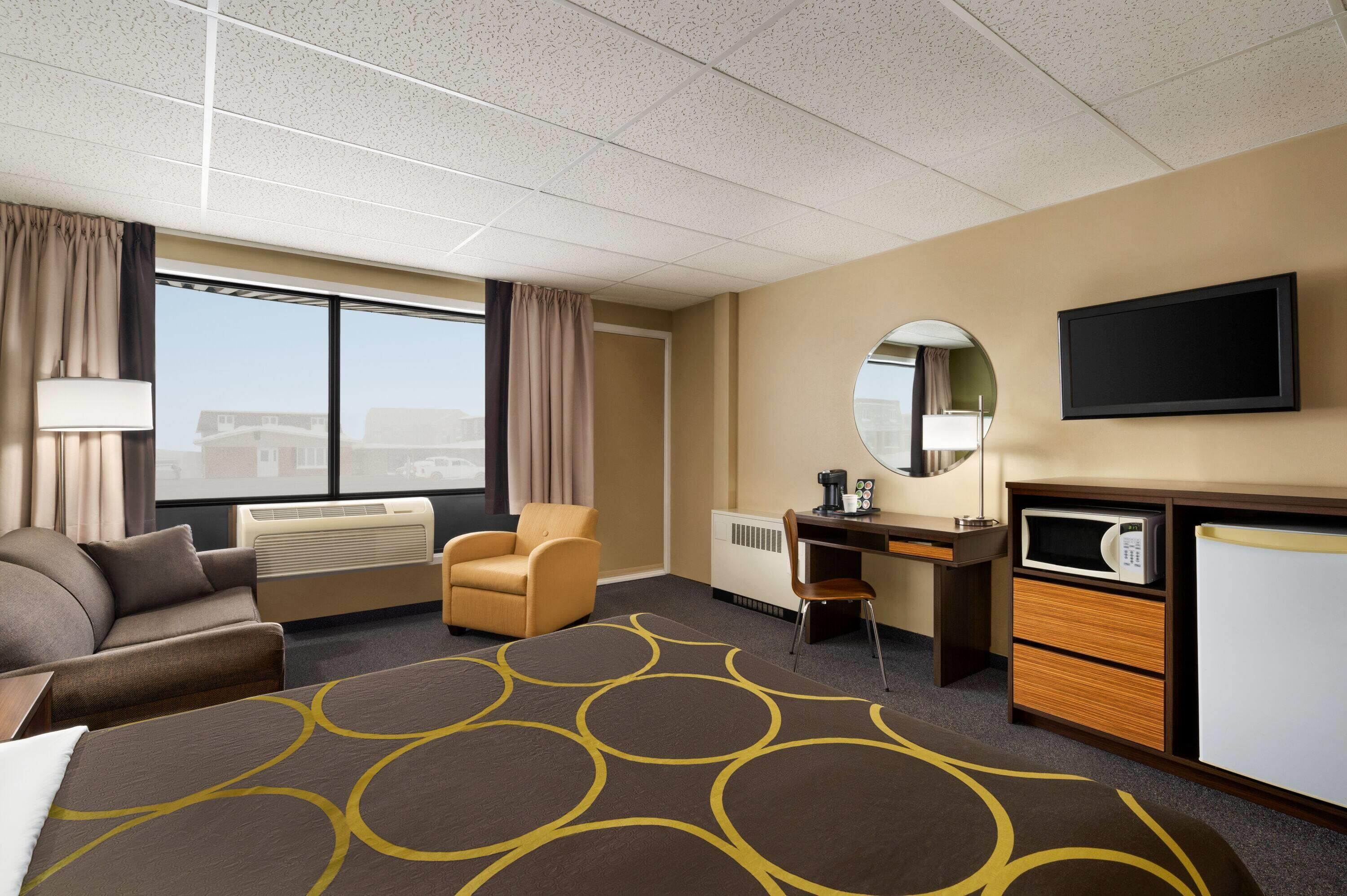 A hotel room with a bed, a desk, a chair, a TV, and a window with curtains.