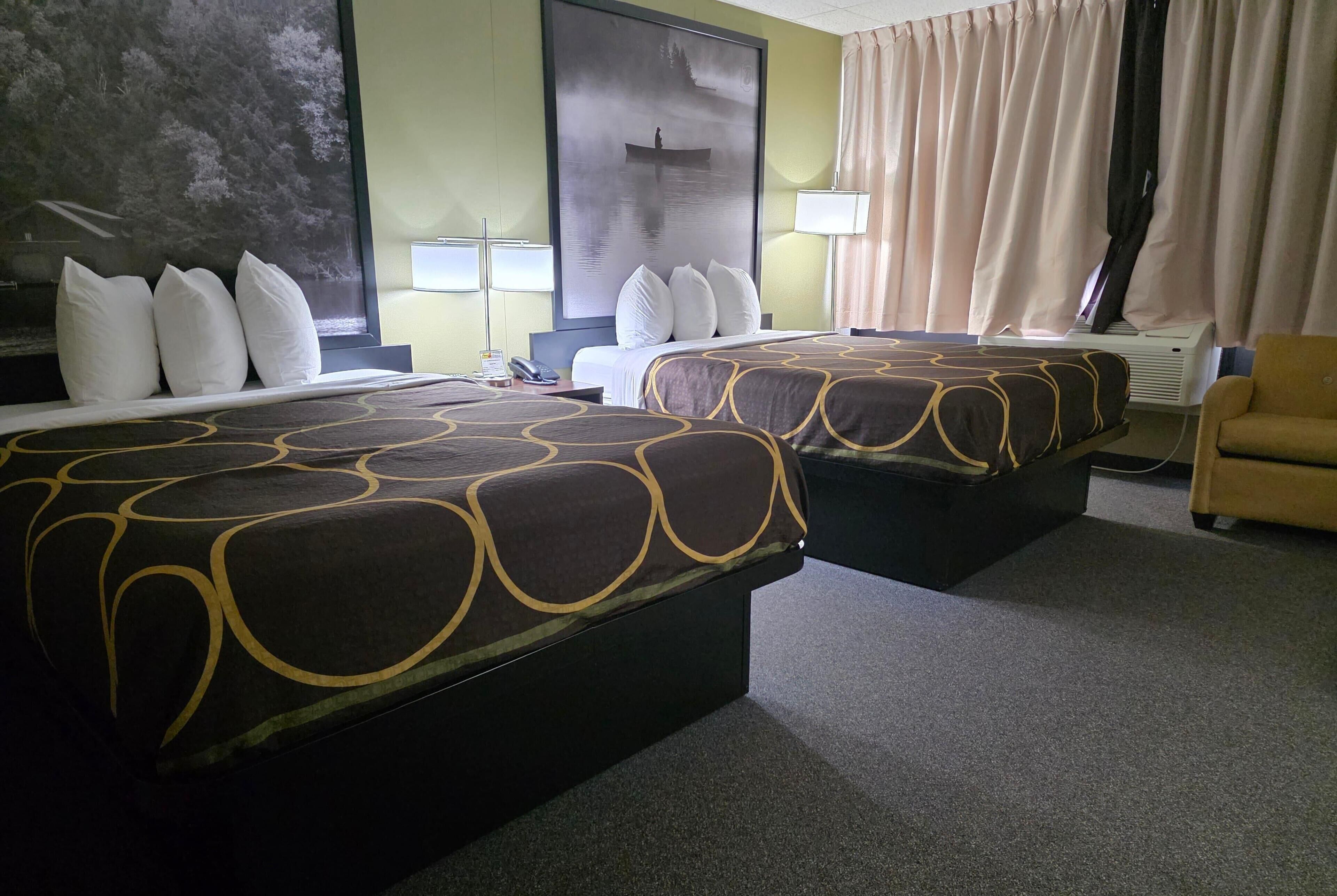 A hotel room with two beds, a large painting, a lamp, and a chair.