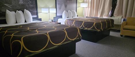 A hotel room with two beds, a large painting, a lamp, and a chair.