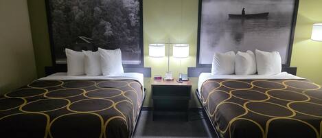 Une chambre d’hôtel avec deux lits, chacun recouvert d’une couvre-lit à motifs, une table de chevet avec une lampe et deux grandes images encadrées accrochées aux murs.