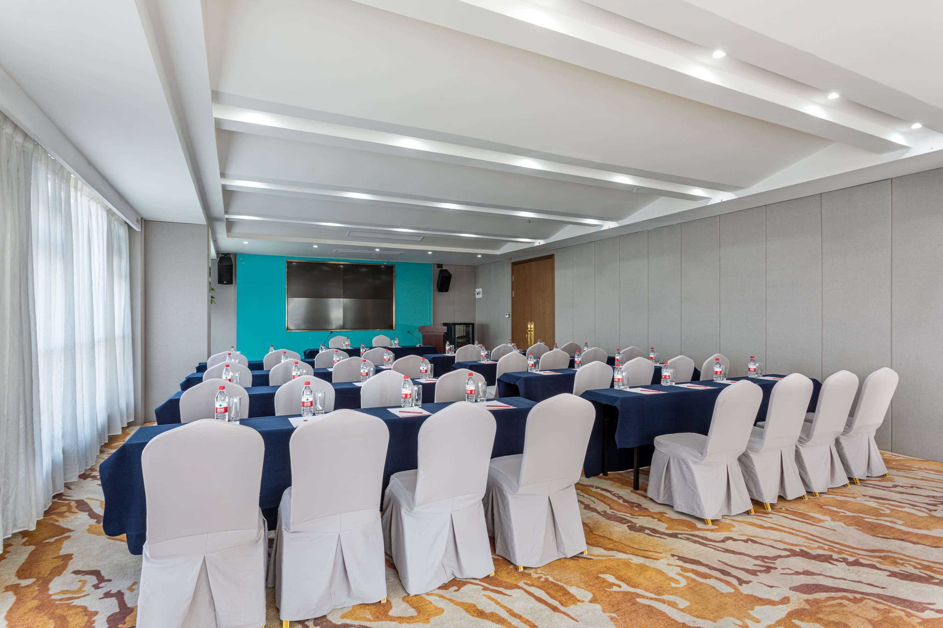 A conference room with multiple tables and chairs, equipped with water bottles and nameplates.