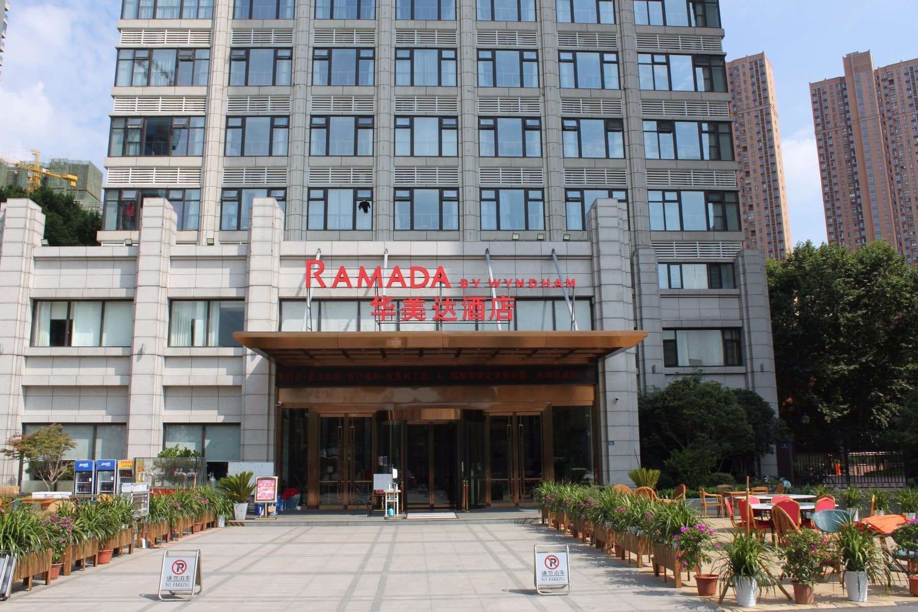Een modern gebouw met een bord waarop 'RAMADA BY WYNDHAM' en Chinese karakters staan.