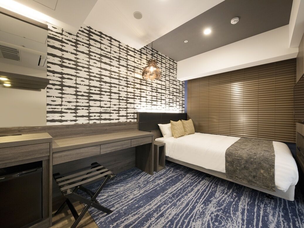 Une chambre d'hôtel moderne avec un grand lit, un bureau et un mur décoré d'un motif.