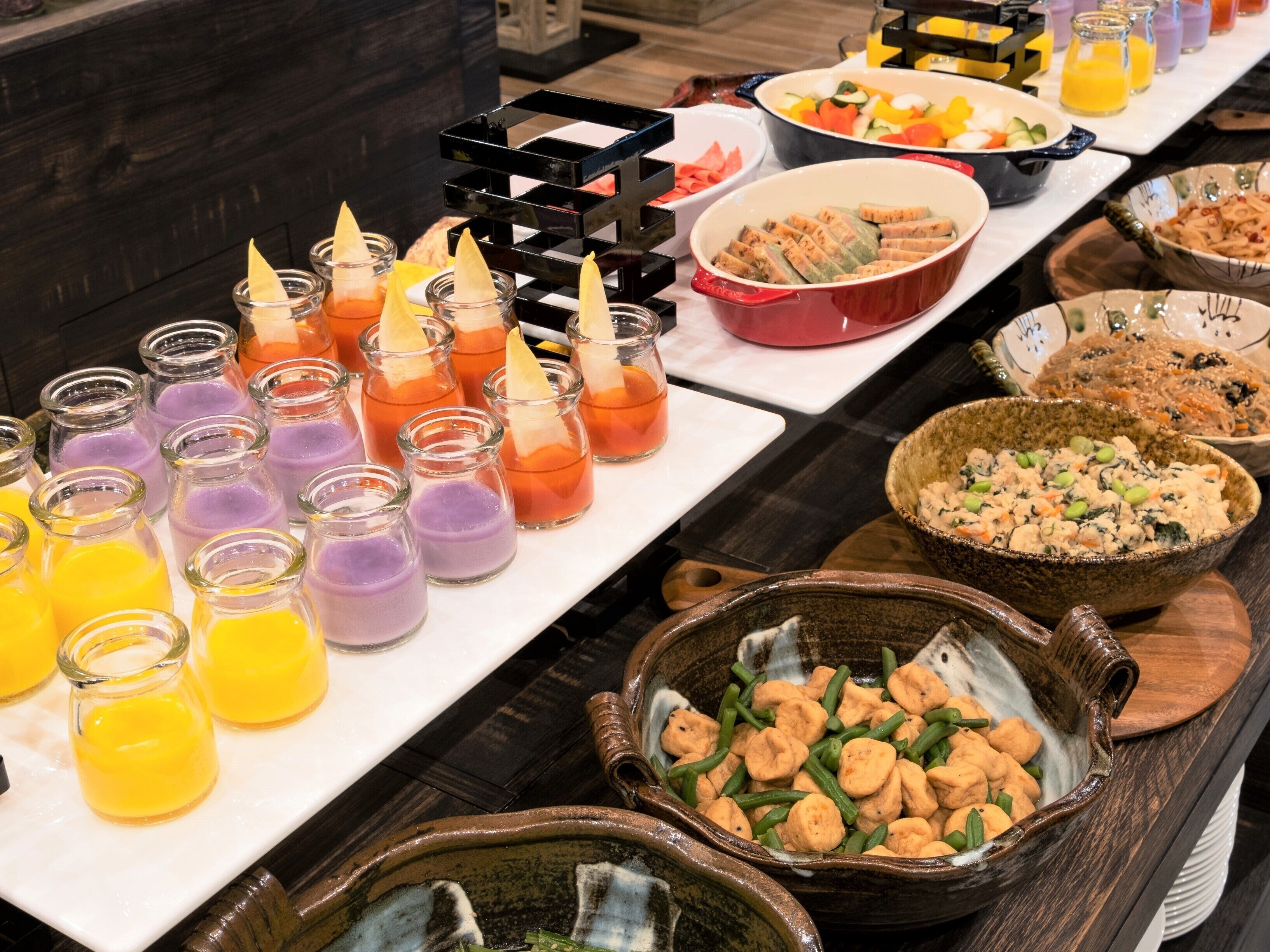 A buffet with various dishes and beverages, including a bowl of green beans and a bowl of shrimp salad.