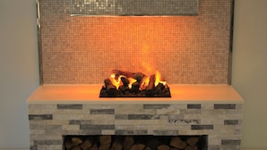 Una chimenea con frente de piedra y pared de azulejos detrás.