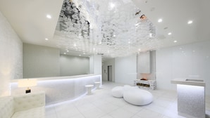 Un baño moderno y minimalista con un espejo grande, una bañera blanca y un diseño de techo único.