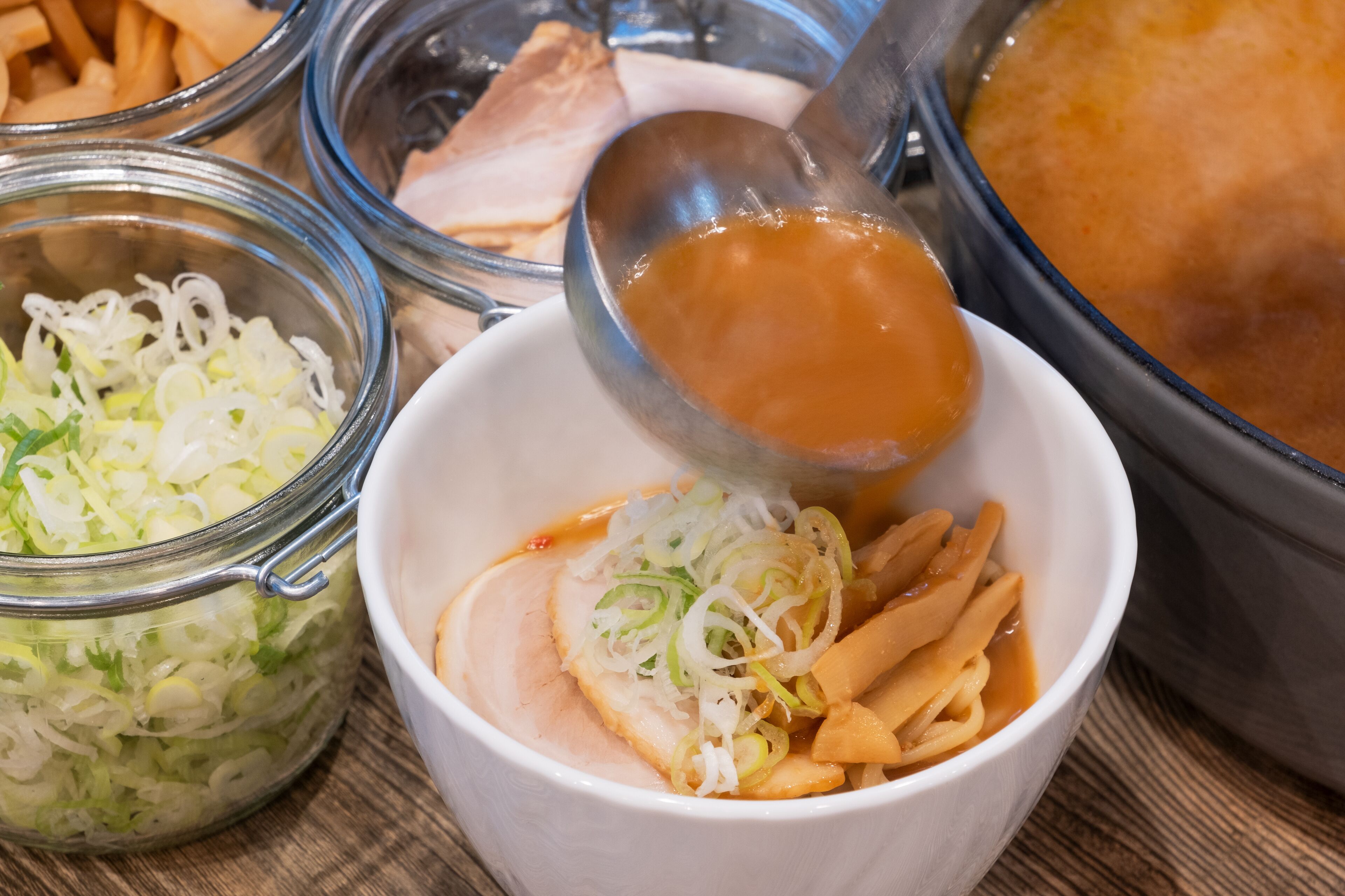 A bowl of food with sliced meat, noodles, and shredded cabbage.