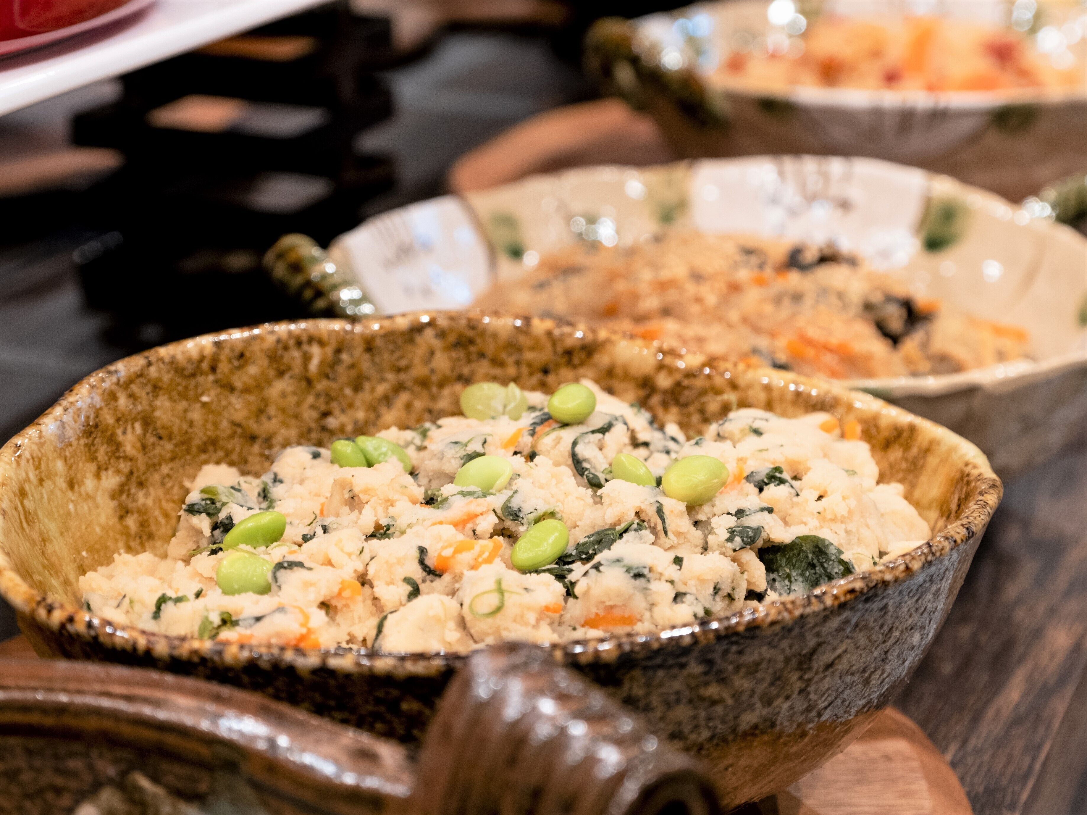 A close-up of a dish with rice, peas, and carrots in a ceramic bowl.