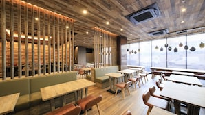 Interior de restaurante con techo de madera, mesas largas y cabinas.