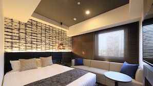 Una habitación de hotel moderna con una cama grande, un sofá, una mesita y una pared con diseño decorativo.