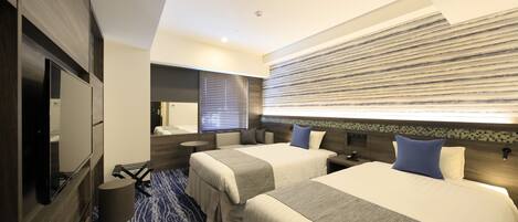 Une chambre d’hôtel avec deux lits, une télévision, un bureau et une salle de bain.
