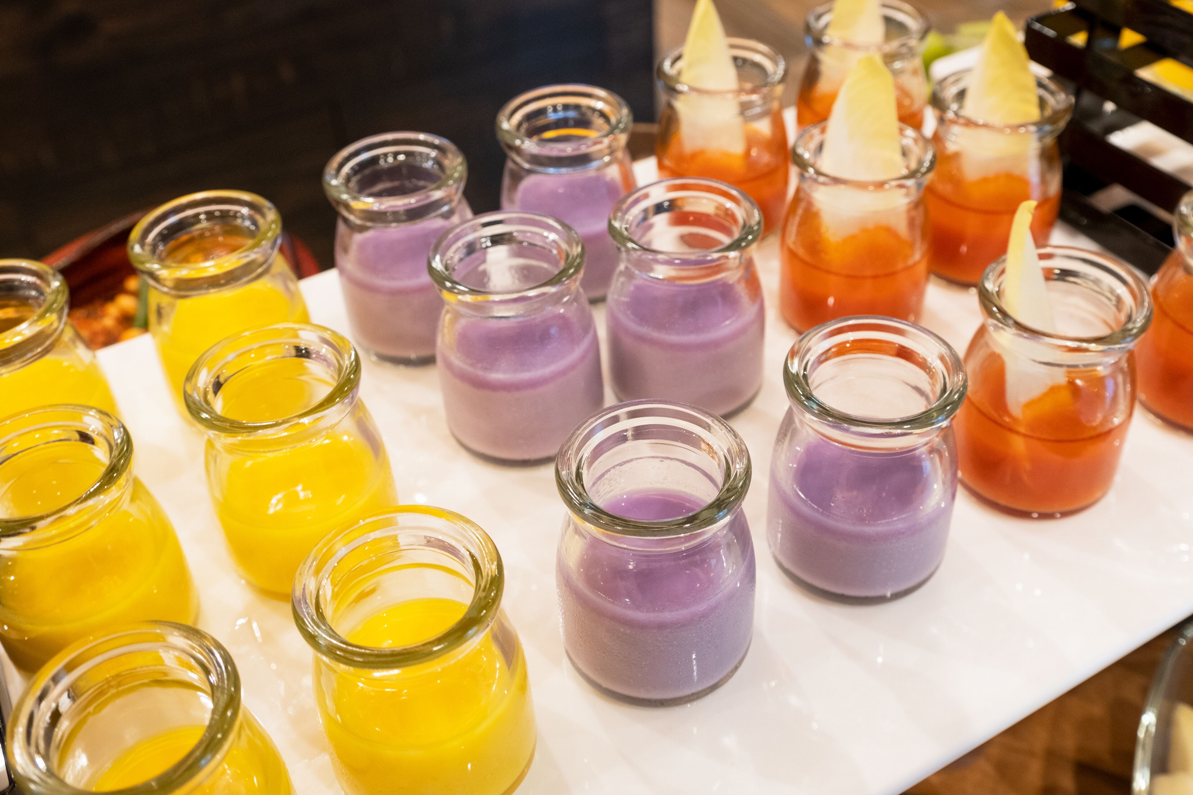 A variety of colorful drinks in small glass bottles, arranged on a white tray.