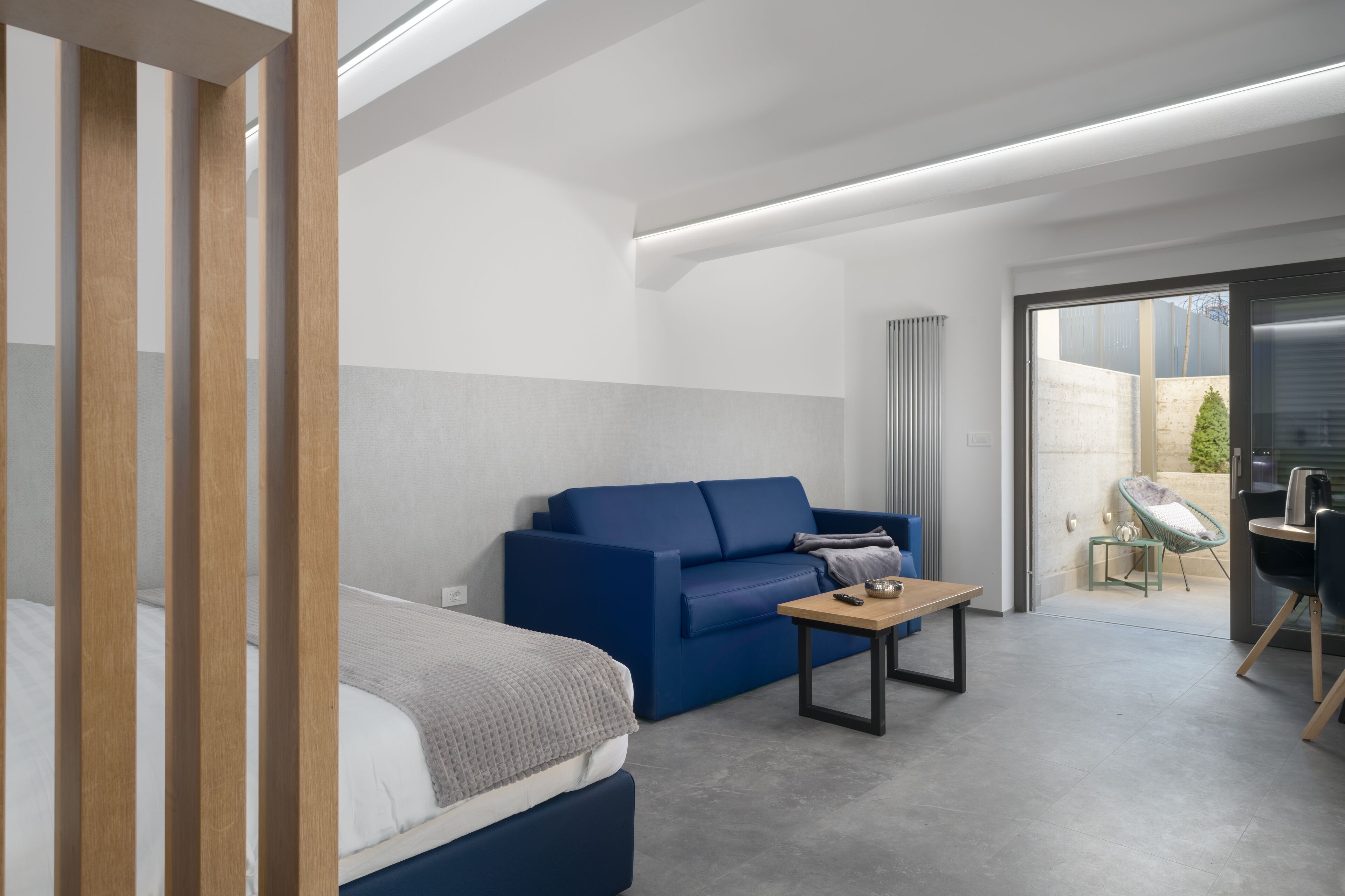 Ein modernes Hotelzimmer mit einem Bett, einer blauen Couch, einem kleinen Tisch und einem Schreibtisch mit Stuhl.