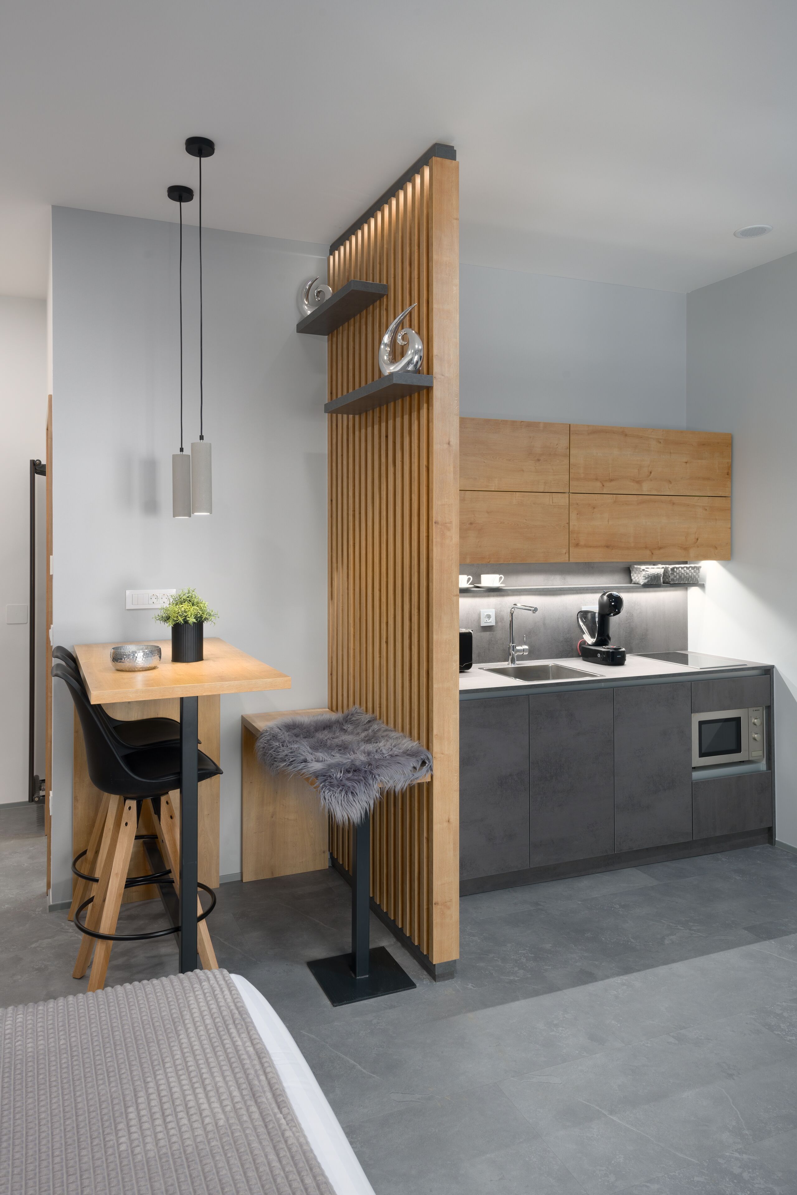 A modern kitchen with a wooden partition, a dining area with a table and chairs, and a small kitchenette.