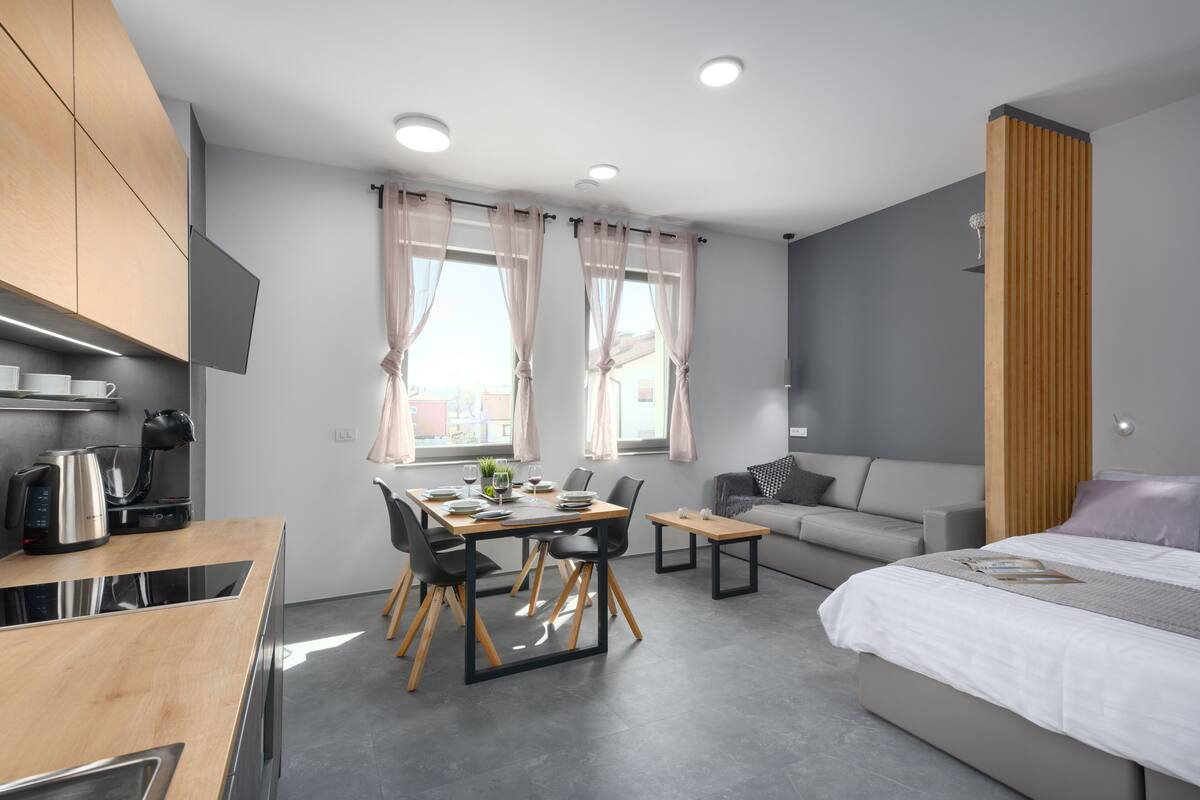 Een moderne hotelkamer met een eethoek, een bank, een bed en een televisie.