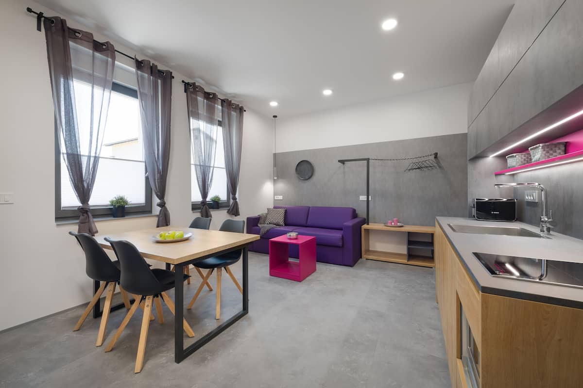 Een moderne keuken met een eethoek, een paarse bank en een klein tafeltje met een roze bijzettafeltje.