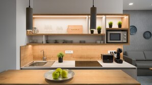 Een moderne keuken met een houten aanrecht, een spoelbak, een magnetron en een broodrooster. Er staan potplanten op het aanrecht en ligt een schaal groene appels op de toonbank.