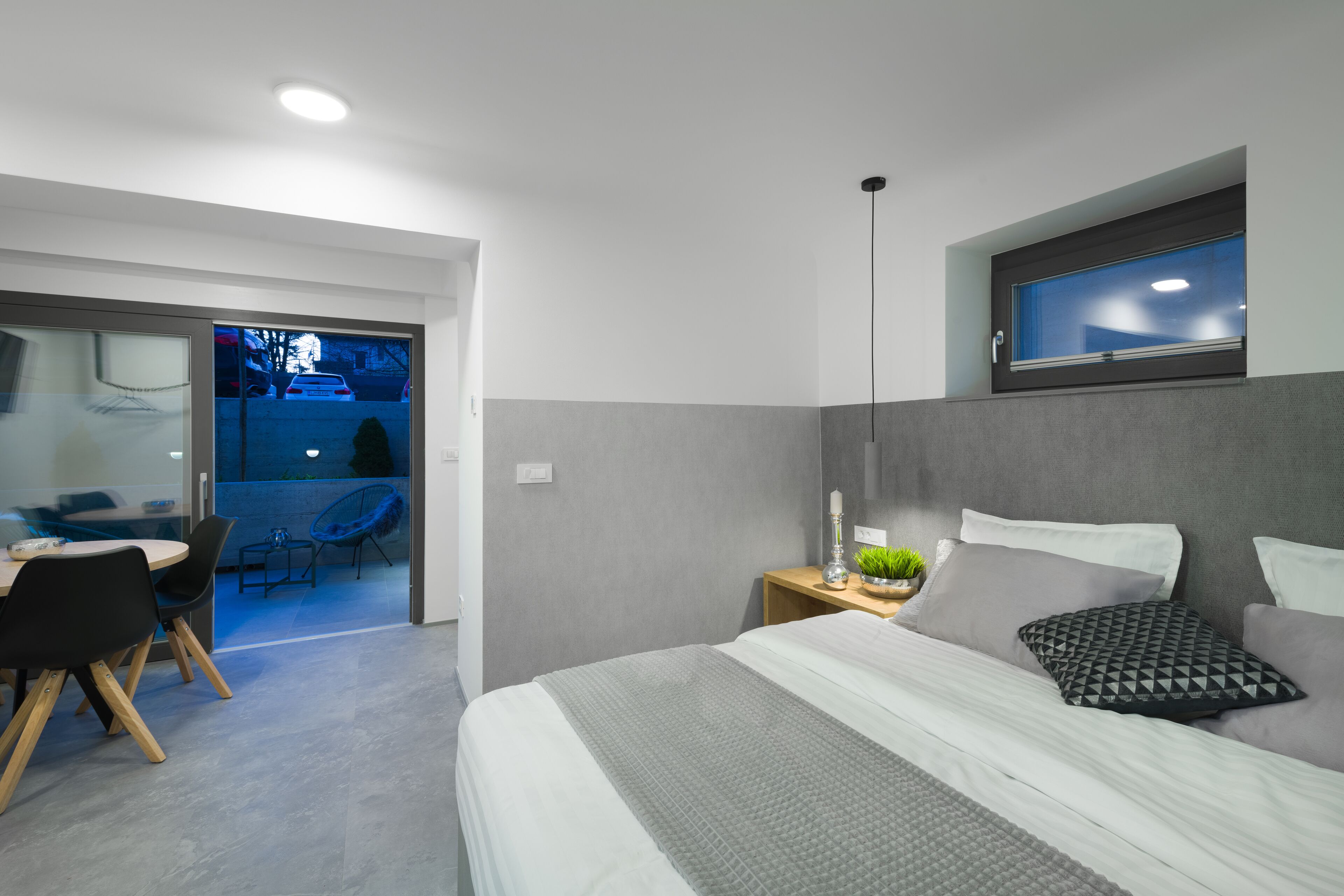 Un dormitorio moderno con cama, mesita de noche y ventana.