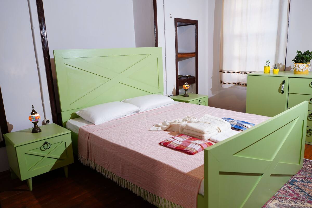 A room with a bed, a nightstand, a dresser, and a mirror.
