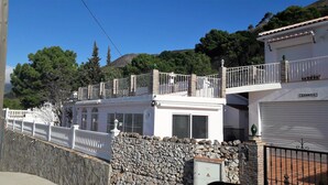 Um edifício de dois andares com varanda, paredes de pedra e garagem.