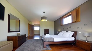 Una camera da letto moderna con un letto di legno, un tappeto grigio, una cassettiera in legno e un grande specchio.