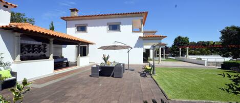 A modern house with a patio, outdoor furniture, and a well-maintained lawn.