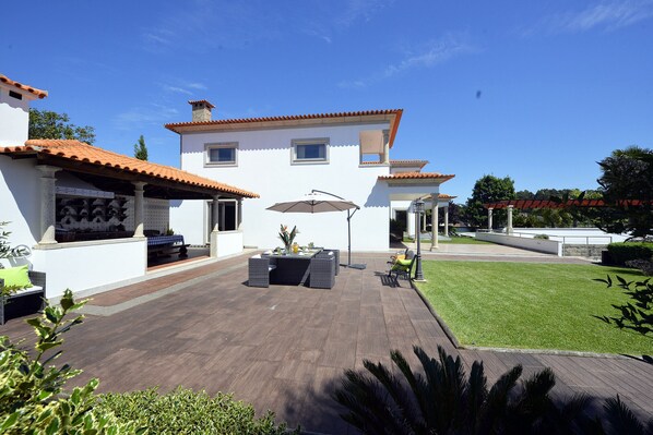 A modern house with a patio, outdoor furniture, and a well-maintained lawn. - Villa 320 Holiday Villa w/Pool, Jacuzzi and Tennis (Barcelos)