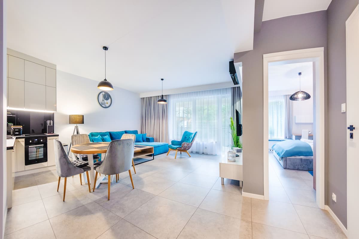 Een modern appartement met een keuken, een eethoek en een woongedeelte. Het heeft een bank, stoelen, een eettafel en een bed.