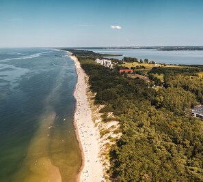 Luchtbeeld van een strand met een dicht bos aan de ene kant en een helder uitzicht op de oceaan.