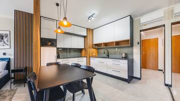 A modern kitchen with white cabinets, a wooden accent wall, and a dining area with a dark wooden table and chairs.