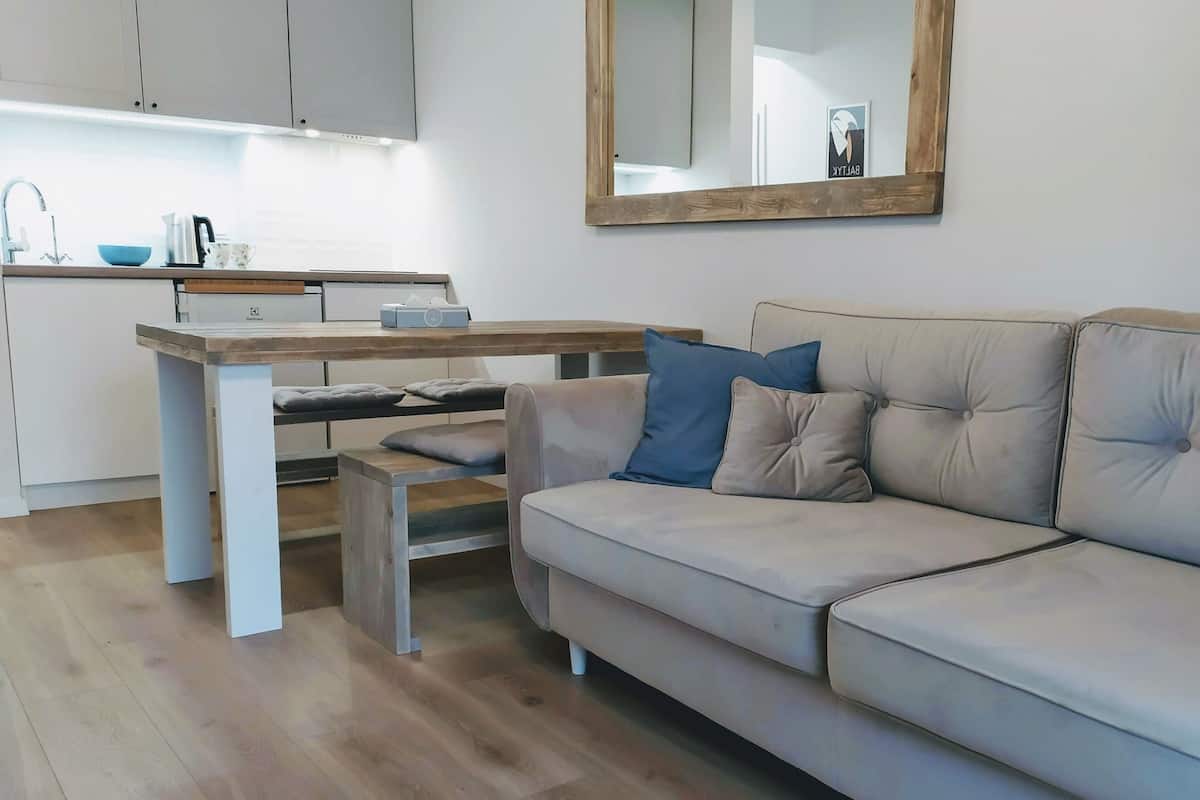 Een moderne woonkamer met een beige bank, een houten eettafel en een keuken op de achtergrond.