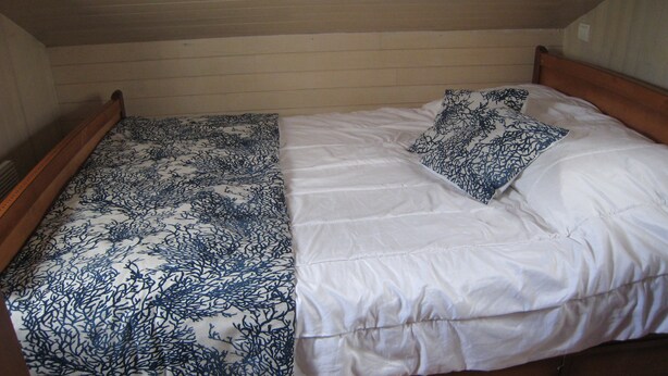 Ein Einzelbett mit weißer Matratze und einem blaumetallfarbenen Bettbezug.